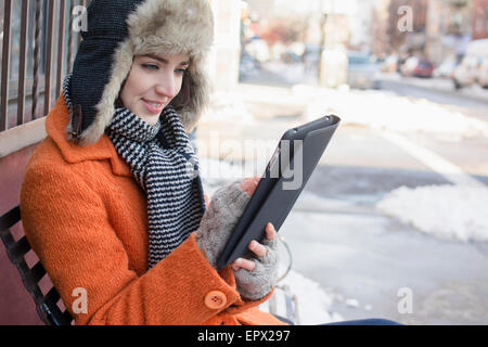 USA, New York, Brooklyn, Frau auf der Bank in der Straße mit tablet Stockfoto