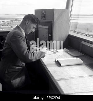 1950, historische, eine männliche Air Traffic Controller an einem Schreibtisch in der Airport Control Tower von der Start- und Landebahn, der Flughafen Dublin, Irland. Stockfoto