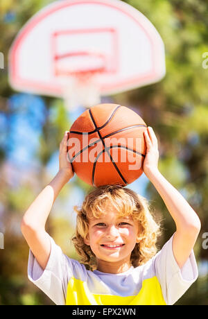 Jungen (8-9) Pflege Basketball auf Kopf Stockfoto