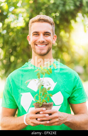 Porträt des jungen Mannes hält Topfpflanze Stockfoto