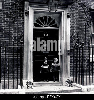 1950er Jahre, historische, zwei kleine Kinder, die hielten die Hände vor dem Eingang zu Nr. 10 Downing Street, Westminster, London, offizielle Residenz des britischen Premierministers. Stockfoto