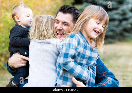 Glückliche Familie mit Baum-Kinder (6-11 Monate, 2-3, 4-5) spielen im Park Stockfoto