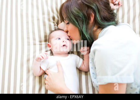 Mutter küssen Baby Boy (6-11 Monate) auf schlecht Stockfoto