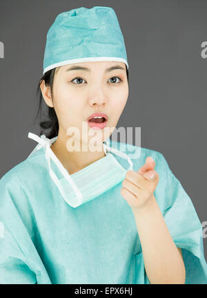Schockiert asiatischen weiblichen Chirurgen mit Hinweis auf farbigem Hintergrund isoliert Stockfoto