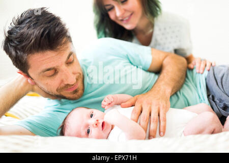 Eltern mit Baby (6-11 Monate) auf schlecht entspannen Stockfoto