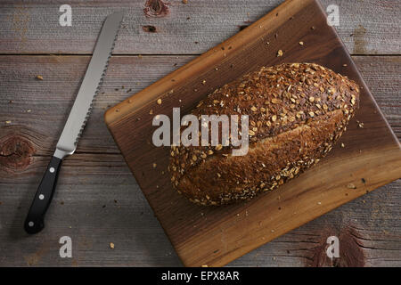 Küchenmesser und Brot auf Holztisch Stockfoto