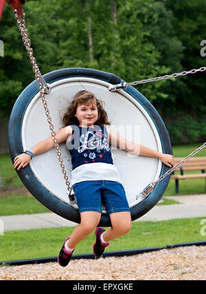 Junges Mädchen schwingt auf einer Untertasse Schaukel auf einem Spielplatz park Stockfoto