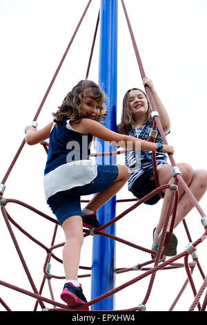 Mädchen spielen am Seil klettern Struktur auf Outdoor-Park Spielplatz Stockfoto