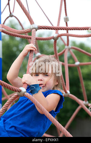 Junges Mädchen spielt auf einer Outdoor-Seilklettern Struktur auf eine Outdoor-Park Spielplatz Stockfoto