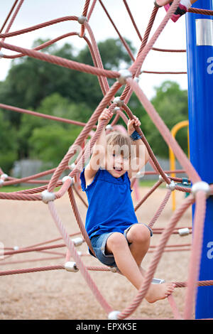 Junges Mädchen spielt an einem Seil klettern Struktur auf eine Outdoor-Park Spielplatz Stockfoto