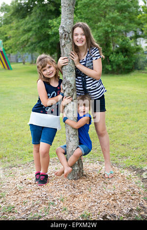 Kinder bereiten Spaß Familienbild auf ein Outdoor-Park Spielplatz beim hängen an einem Baumstamm Stockfoto