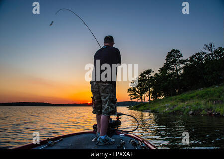 Fischer am Bug des Bass Boot Angeln bei Sonnenuntergang für forellenbarsch McGee Creek Lake in Oklahoma. Stockfoto