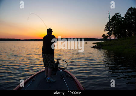 Fischer am Bug des Bass Boot Angeln bei Sonnenuntergang für forellenbarsch McGee Creek Lake in Oklahoma. Stockfoto