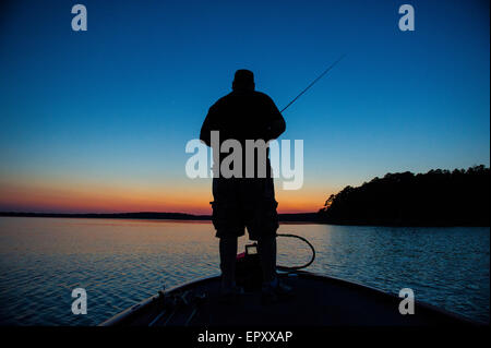 Fischer am Bug des Bass Boot Angeln bei Sonnenuntergang für forellenbarsch McGee Creek Lake in Oklahoma. Stockfoto