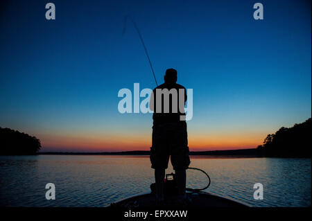 Fischer am Bug des Bass Boot Angeln bei Sonnenuntergang für forellenbarsch McGee Creek Lake in Oklahoma. Stockfoto