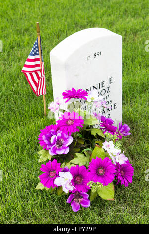 Eine amerikanische Flagge und Blumen an Grabstätten von Freiwilligen in Vorbereitung für Memorial Day in Fort Sam Houston National Cemetery platziert. Stockfoto