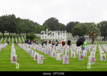 Freiwillige setzen amerikanische Flaggen an Grabstätten im Regen während der Memorial Day Vorbereitungen in Fort Sam Houston National Cemetery Stockfoto