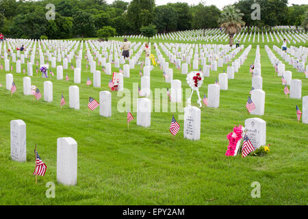 Junge platzieren Pfadfinder und andere freiwillige amerikanische Flaggen an Grabstätten bei Memorial Day Vorbereitungen in Fort Sam Houston National Cemetery. Stockfoto