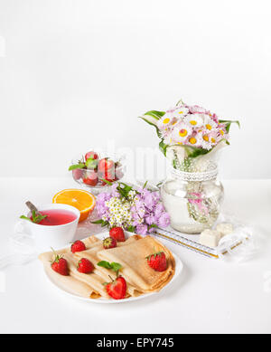 Pfannkuchen, Orange, Erdbeere und Hibiskus Tee mit Blumenstrauß beim Frühstück auf den Tisch Stockfoto