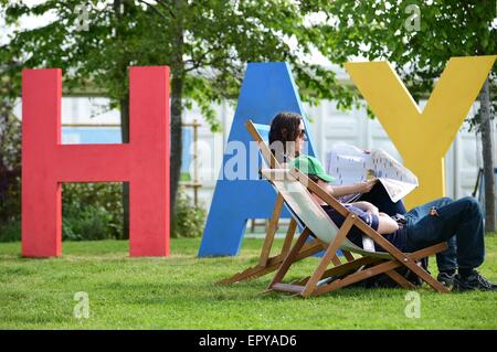 Hay on Wye. Wales UK. Samstag, 23. Mai 2015 paar sitzen in Liegestühlen durch das riesige Heu Zeichen genießen die warme Sonnenstrahlen auf der Eröffnung Samstag des Literaturfestivals Heu photo Credit: Keith Morris / Alamy Live News Stockfoto