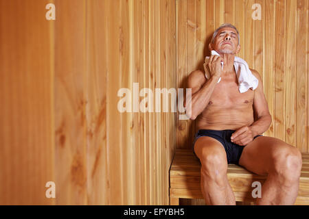 Alter Mann mit Handtuch zum Entspannen in der Sauna des Hotels Stockfoto