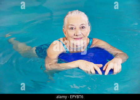 Alte Frau Schwimmen im Wasser mit Kickboard in einem Hotelpool Stockfoto