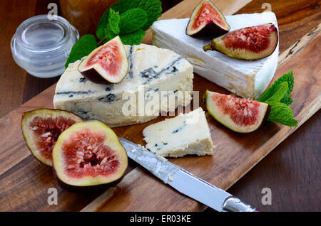 Frische Feigen auf Holz schneiden Schneidebrett mit Glas Feigen Gelee Konserve und Gourmet-Käse auf dunkel rustikalen Holztisch staatlich Stockfoto