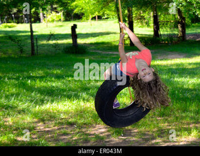 Elementare gealterten Mädchen schwingen auf einer Reifenschaukel in der hellen Frühlingssonne Stockfoto