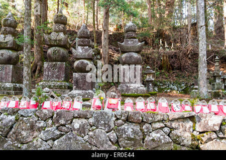 Der alte Okunoin Friedhof bei Koyasan in Japan. Reihe von roten Bibbed Izo Statuen vor fünf-Element Pagoden, Gorinto, in der Zedernbaum Wald. Stockfoto