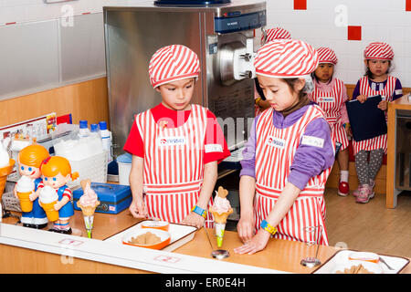 Kinderaktivitätszentrum Kidzania in Nishinomiya, Japan. Gruppe von Kindern lernen, wie man Eis mit Lehrer helfen zu machen und zu dekorieren. Stockfoto