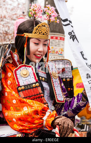 Junge Frau in Heian-Zeit-Kostüm eines Samurai-Kriegers mit mae-Tengan-Kopfkleid, auf weißem Pferd bei der Genji-Parade in Tada, Japan. Stockfoto