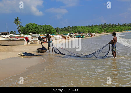 Männer mit Fischernetzen am tropischen Strand von Pasikudah Bay, Eastern Province, Sri Lanka, Asien Stockfoto