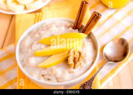 Frische leckere heiße Haferflocken Brei mit Apfelscheiben, Nüssen und Zimt auf Serviette und Holztisch. Gesundes Bio-Frühstück Stockfoto