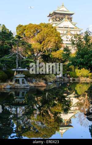 Osaka Castle Keep, im Borogata-Stil, ragt über dem japanischen Garten des Kishu Palace und spiegelt sich im Teich. Steinlaterne im Vordergrund. Stockfoto