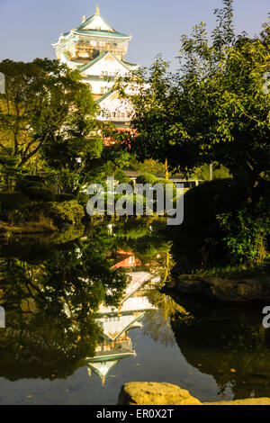 Osaka Castle Keep, Borogata-Stil, beleuchtet bei Nacht und auch im Teich im japanischen Garten des Kishu Palace reflektiert. Blauer Himmel. Stockfoto