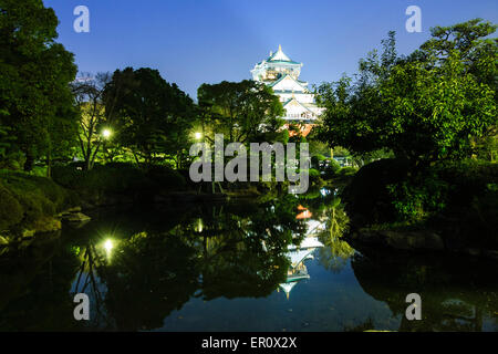 Osaka Castle Keep, Borogata-Stil, beleuchtet bei Nacht und auch im Teich im japanischen Garten des Kishu Palace reflektiert. Blauer Himmel. Stockfoto