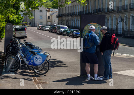 Zwei Touristen Männer lesen eine Informationskarte bemerken neben elektrischen Leihräder in der Stadt Bath, UK Stockfoto