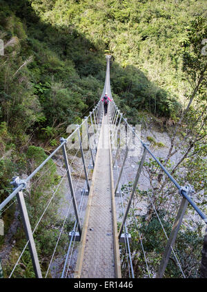 Eine weibliche Walker über eine lange Hängebrücke auf dem Roberts Trail nach Franz Josef Glacier auf Neuseelands Südinsel Stockfoto