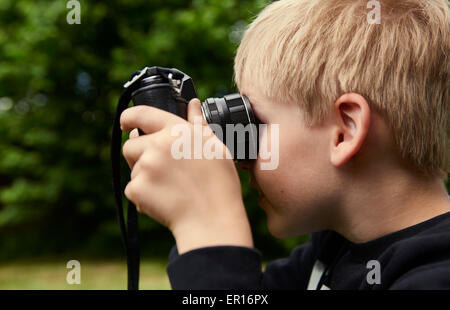 Kind blonde junge mit dem Vintage Photo Film Retro-Kamera fotografieren außerhalb. Selbst - Selfie fotografieren Stockfoto