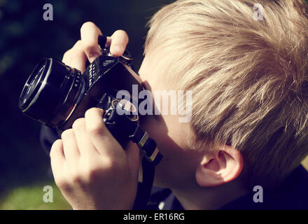 Kind blonde junge mit Vintage Foto Film Kamera fotografieren außerhalb Stockfoto