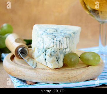 Stück Blauschimmelkäse mit grünen Trauben auf einem Holzbrett Stockfoto