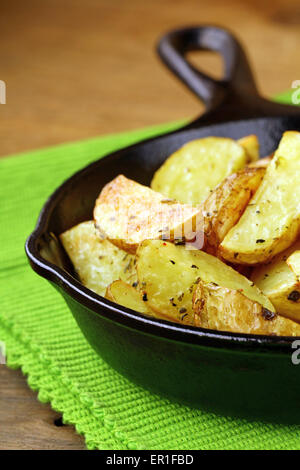 Scheiben vom gebratenen Kartoffeln mit Gewürzen in einer gusseisernen Pfanne Stockfoto