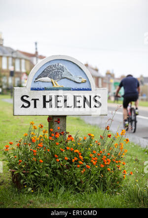 Ein Radsportler, die hinter dem Ortsschild von St. Helens (AKA Goose Island) neben dem Grün auf der Isle Of Wight. Stockfoto