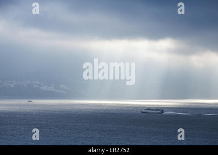 Volumen-Sonnenlicht geht durch dunkle blaue Wolken. Bucht von Tanger, Marokko, Afrika Stockfoto