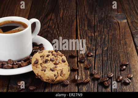 Kaffeetasse mit Schoko-Cookie auf dunklem Holz Stockfoto