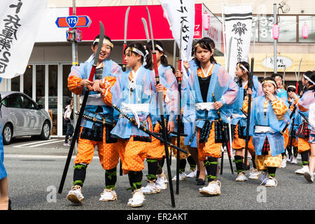 Ein Team von Kindern, Mädchen, die als Shimobe-Soldaten der Heian-Ära verkleidet in der Frühlingsparade von Genji durch die Stadtstraße in Tada, Japan marschieren. Stockfoto