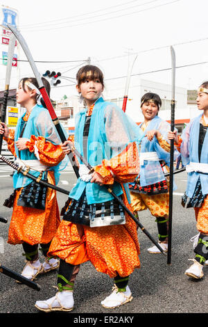 Ein Team von Kindern, Mädchen, die als Shimobe-Soldaten der Heian-Ära verkleidet in der Frühlingsparade von Genji durch die Stadtstraße in Tada, Japan marschieren. Stockfoto