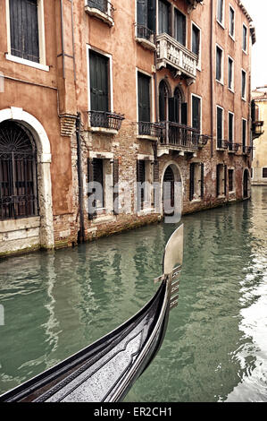 Eine venezianische Gondel an einem regnerischen Tag in einen kleinen Kanal in Venedig, Italien, mit historischen Gebäuden und alten Wasser Türen Bug Stockfoto