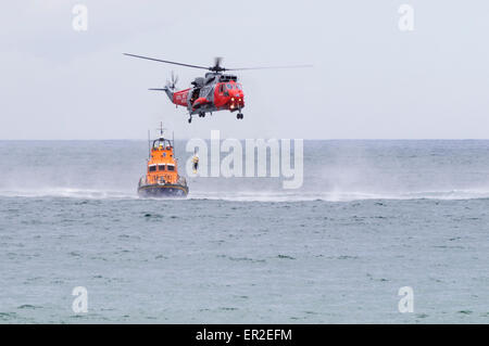 Ein Hubschrauber Winden als RNLB Rettungsboot wartet einen Mann an Bord. Stockfoto