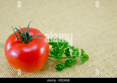 Rohe Tomaten auf einem gedeckten Tisch mit frischer Petersilie Stockfoto